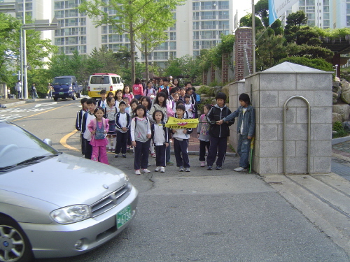 도시 학교, 교문을 들어서는 데도 차량 통행에 밀려 제지를 받아야 한다 